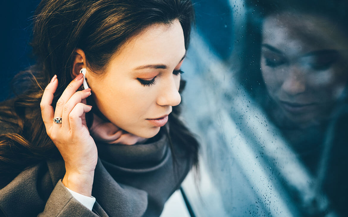 Murlher no metro com fones de ouvindo, escutando a um podcast